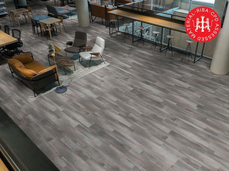 Grey Amtico LVT flooring in a space with sofas, armchairs, stools and tables.